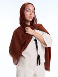 Woman wearing a brown hijab and white outfit on a white background