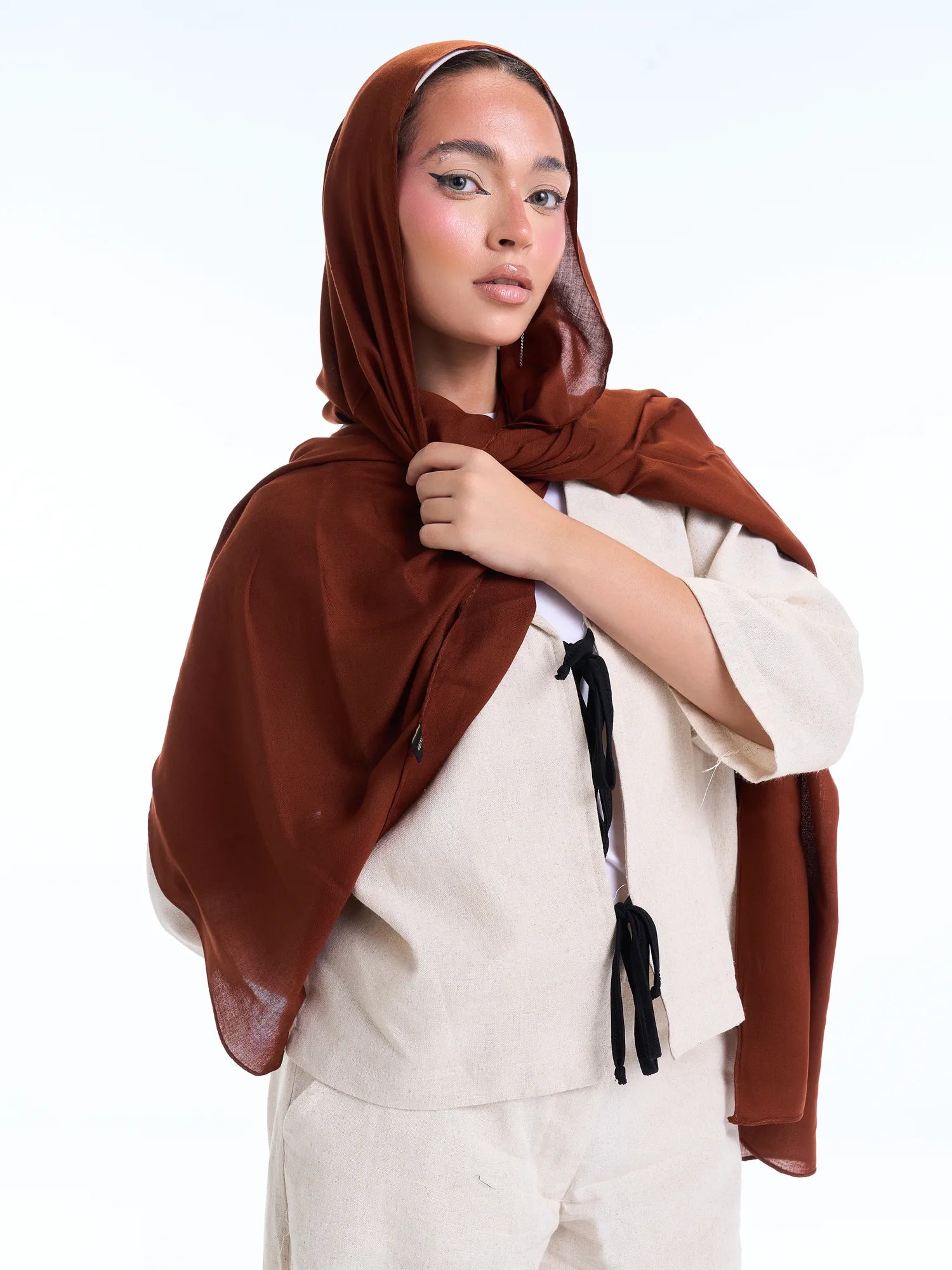 Woman wearing a brown hijab and white outfit on a white background