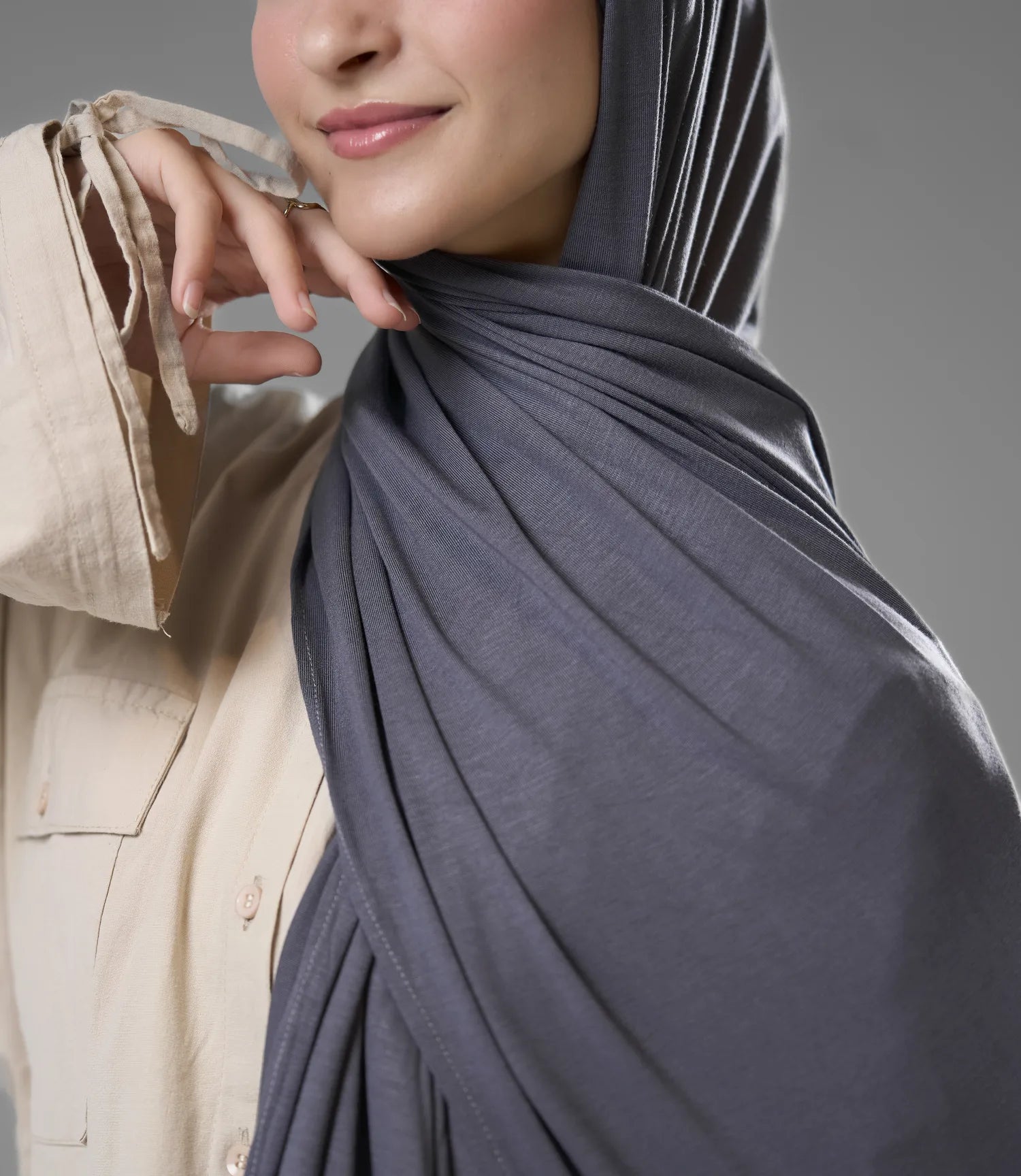 Person wearing a gray hijab with a neutral background