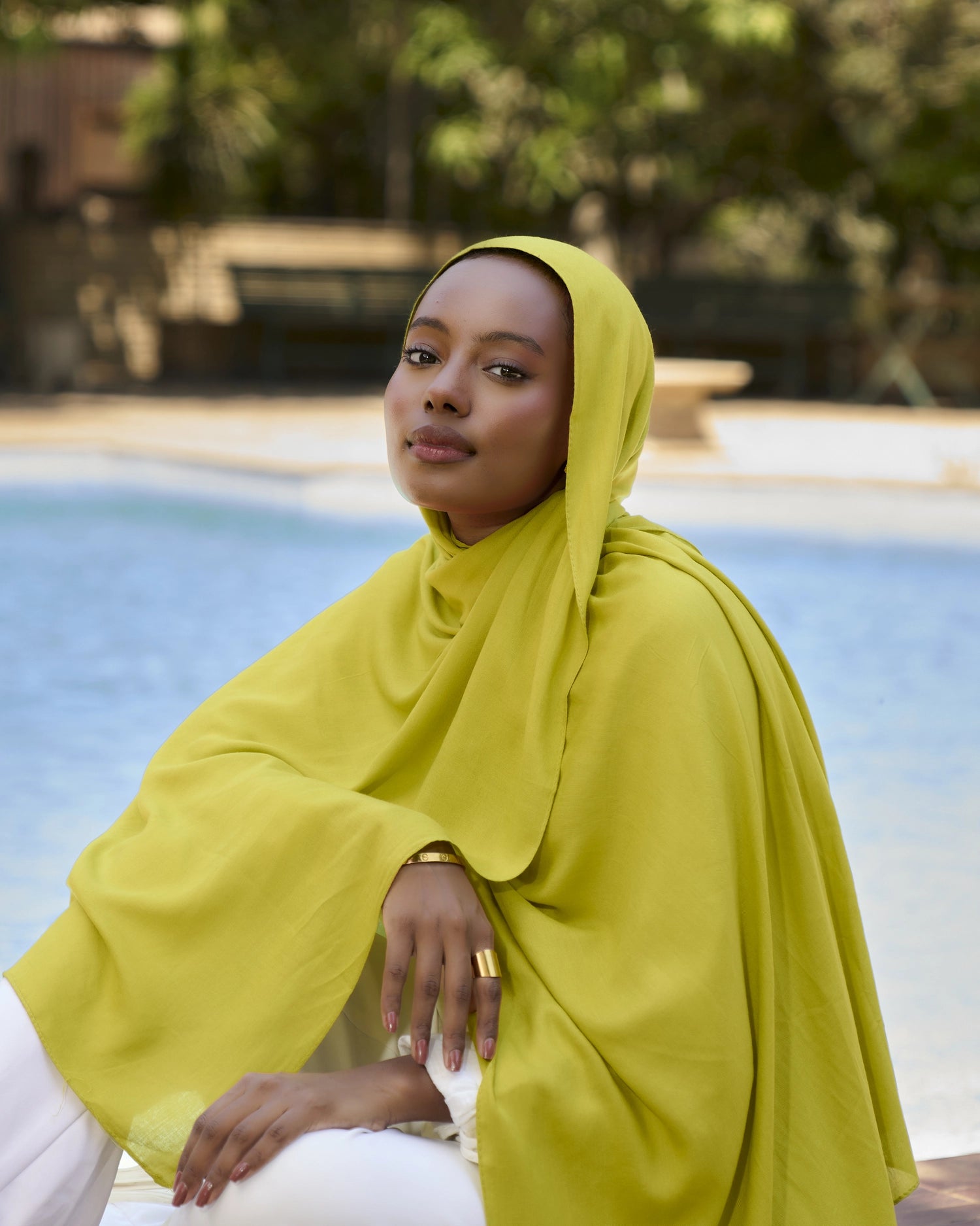Woman wearing a bright yellow hijab by a poolside