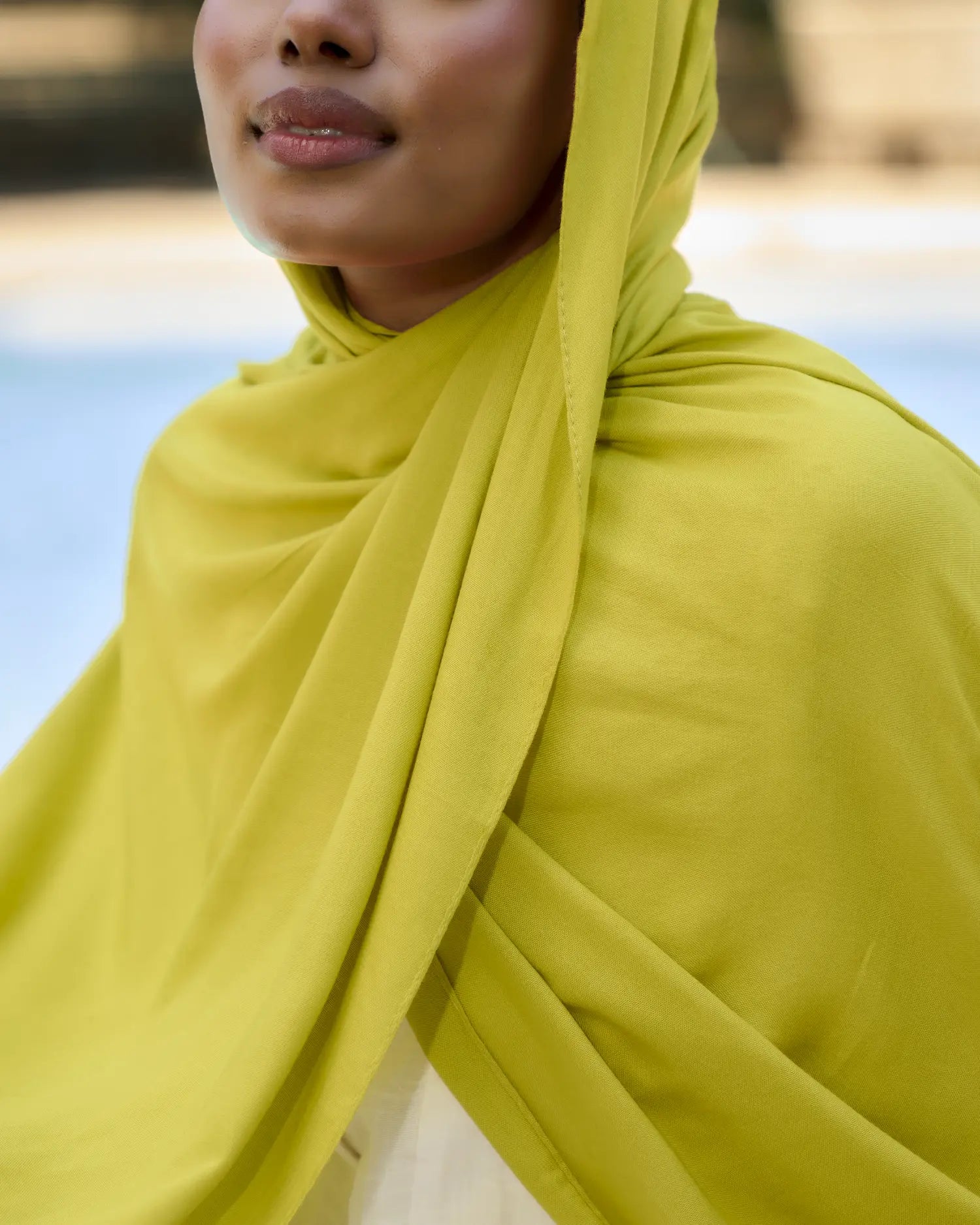 Person wearing a bright yellow hijab with a blurred natural background