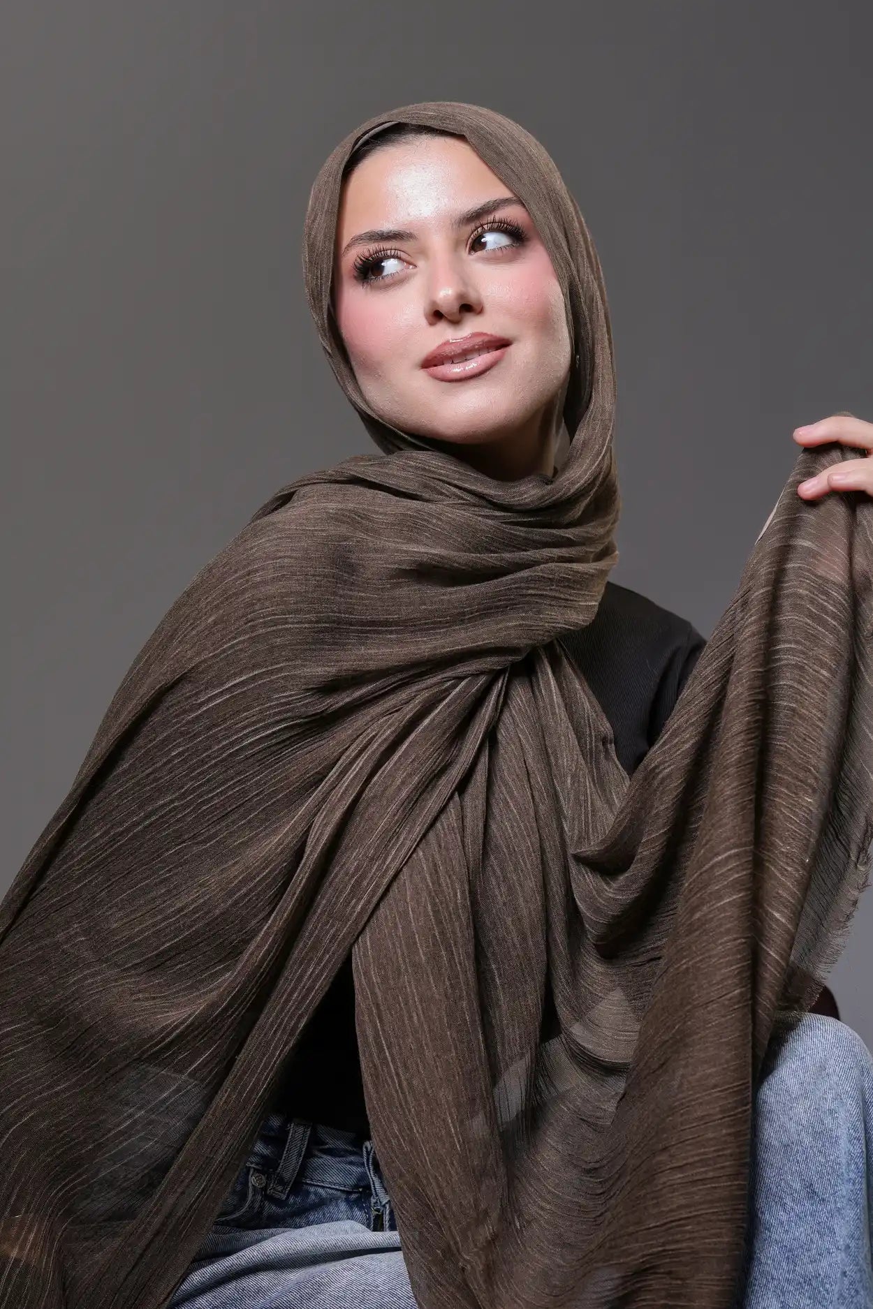 Woman wearing a brown hijab against a gray background