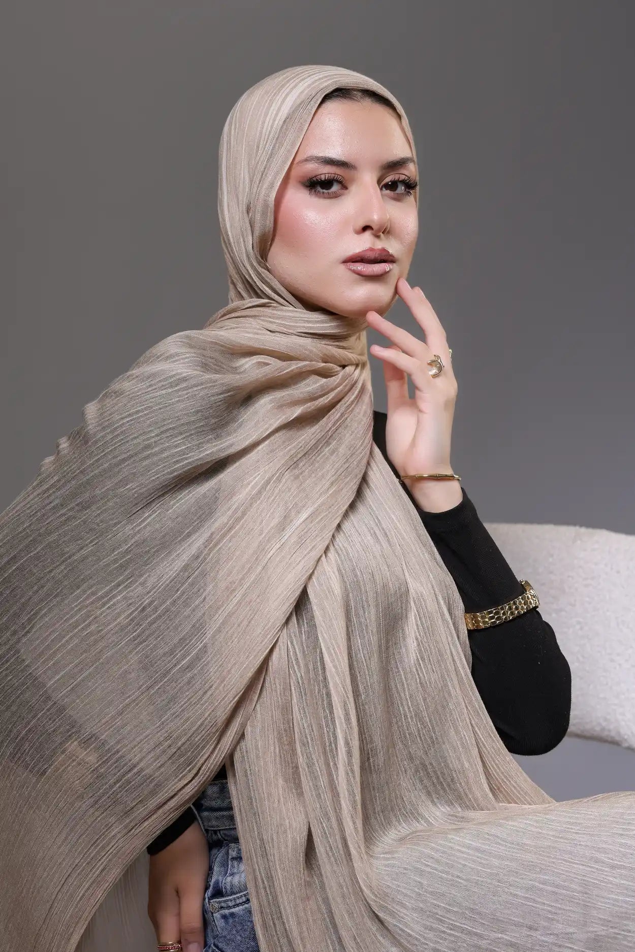 Woman wearing a beige hijab against a gray background
