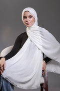 Woman wearing a white hijab against a gray background