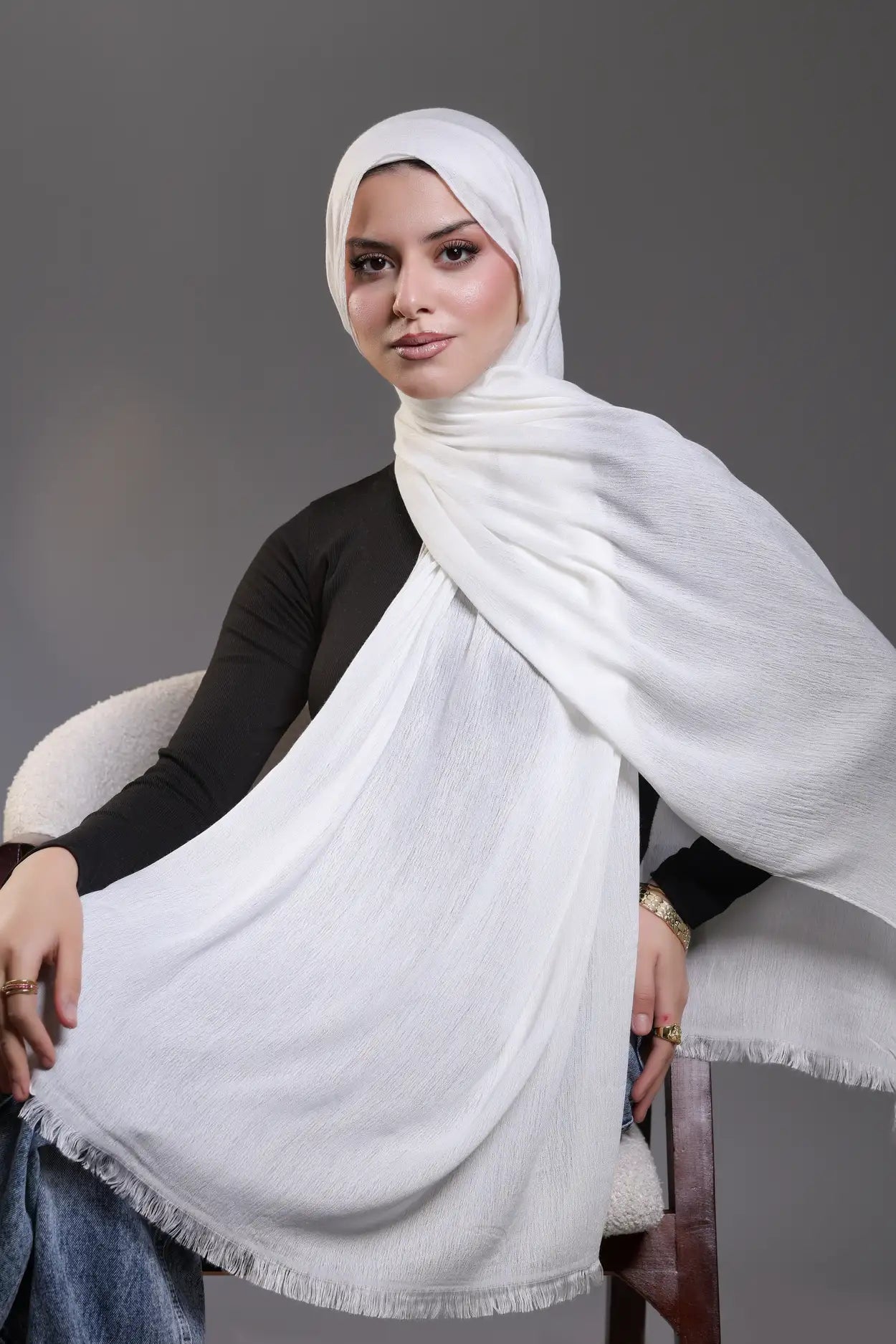 Woman wearing a white hijab against a gray background