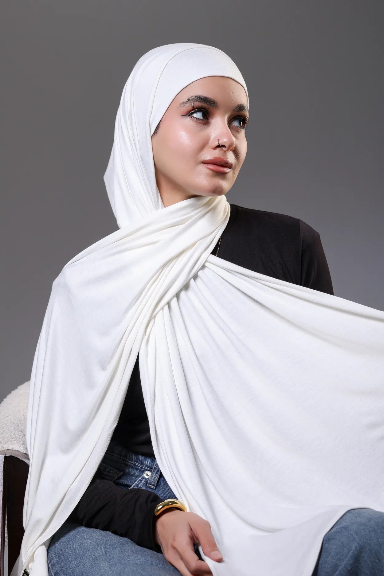 Woman wearing a white hijab against a gray background