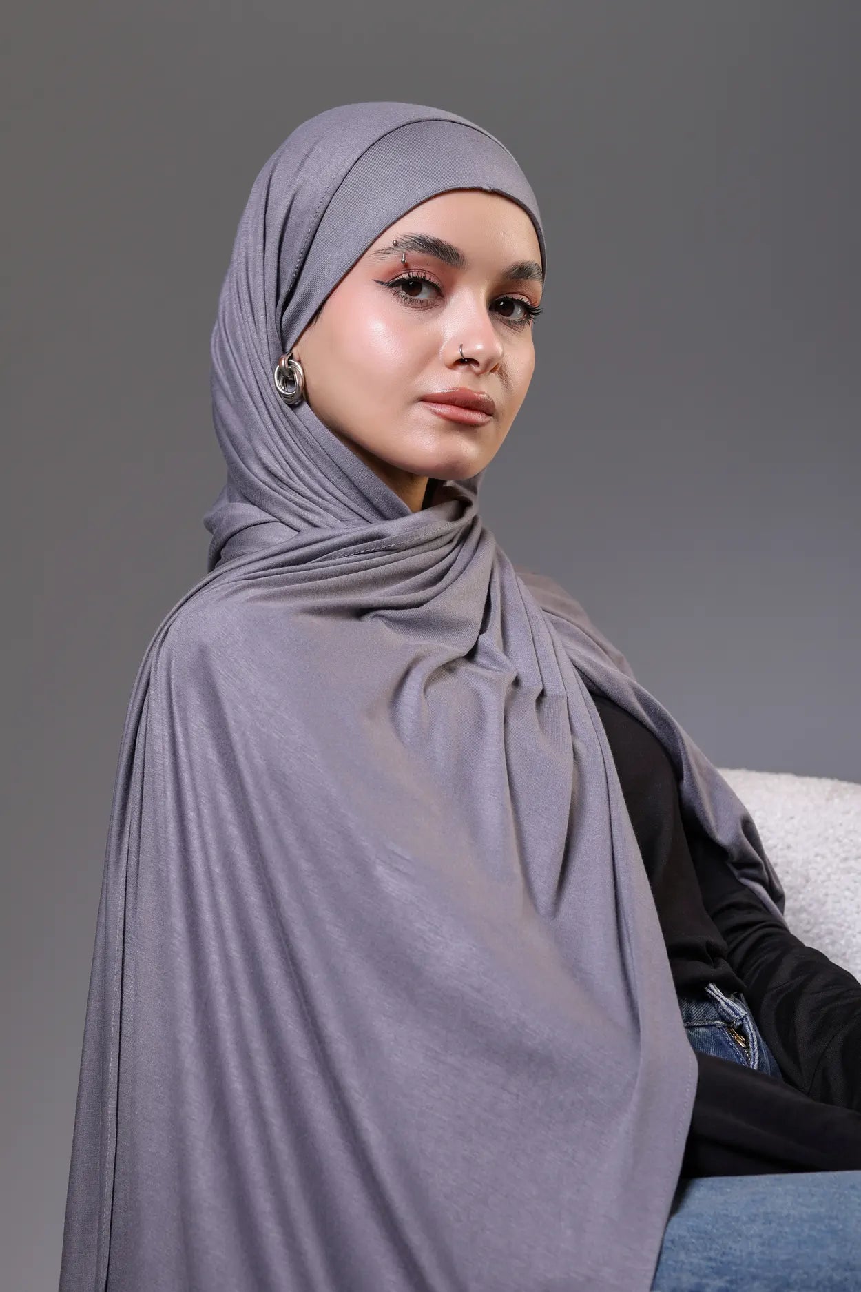 Woman wearing a gray hijab against a gray background