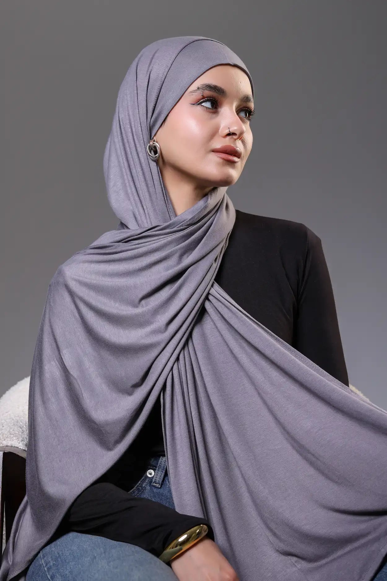 Woman wearing a gray hijab against a gray background