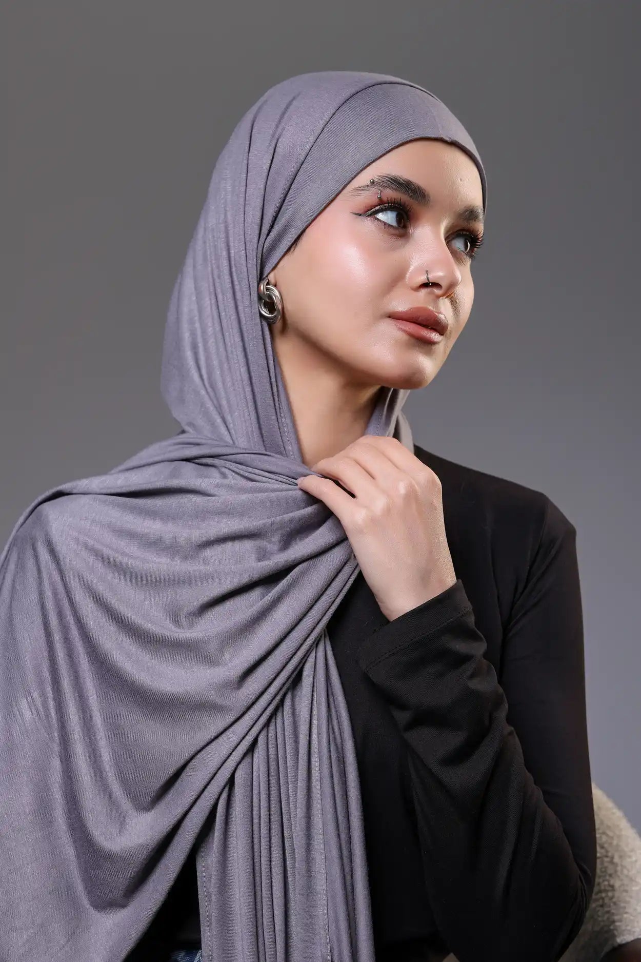 Woman wearing a gray hijab against a gray background